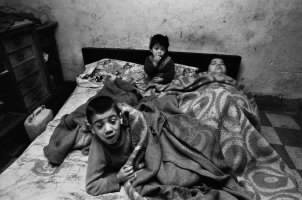 La donna e i suoi bambini stanno sempre a letto. In casa non ci sono né luce né acqua. Palermo, 1978.&nbsp;

