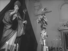 fig. 8 La statua del santo e le offerte rituali recanti richieste di grazia, fotogramma da Il male di san Donato (1965) di Luigi Di Gianni

