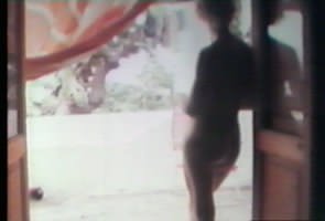 Laura nuda sulla soglia di una portafinestra. Luca Ferro, Trascorrere con Laura, 8mm, 1974-2021. Per gentile concessione dell&rsquo;autore.
