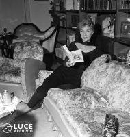 Fig. 1 Elsa de&rsquo; Giorgi legge un libro sul divano del salotto, s.d. &copy;Archivio Storico Istituto Luce.
