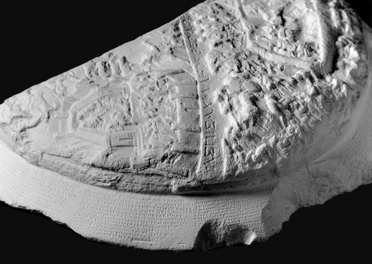Ph. of text around the obverse rim of Tabula Iliaca 4N (cf. Fig. 3b); Il. 18.483–492 (top), vv. 493–504 (upper centre) and vv. 505–519 (lower centre); a fourth column, to the right (on the damaged part of the rim at the bottom) was inscribed with vv. 533–545. (Ph. by Stefan Eckardt) Ph. of text around the obverse rim of Tabula Iliaca 4N (cf. Fig. 3b); Il. 18.483–492 (top), vv. 493–504 (upper centre) and vv. 505–519 (lower centre); a fourth column, to the right (on the damaged part of the rim at the bottom) was inscribed with vv. 533–545. (Ph. by Stefan Eckardt)